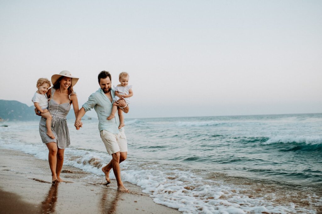 A couple holding hands on the beach with their two children