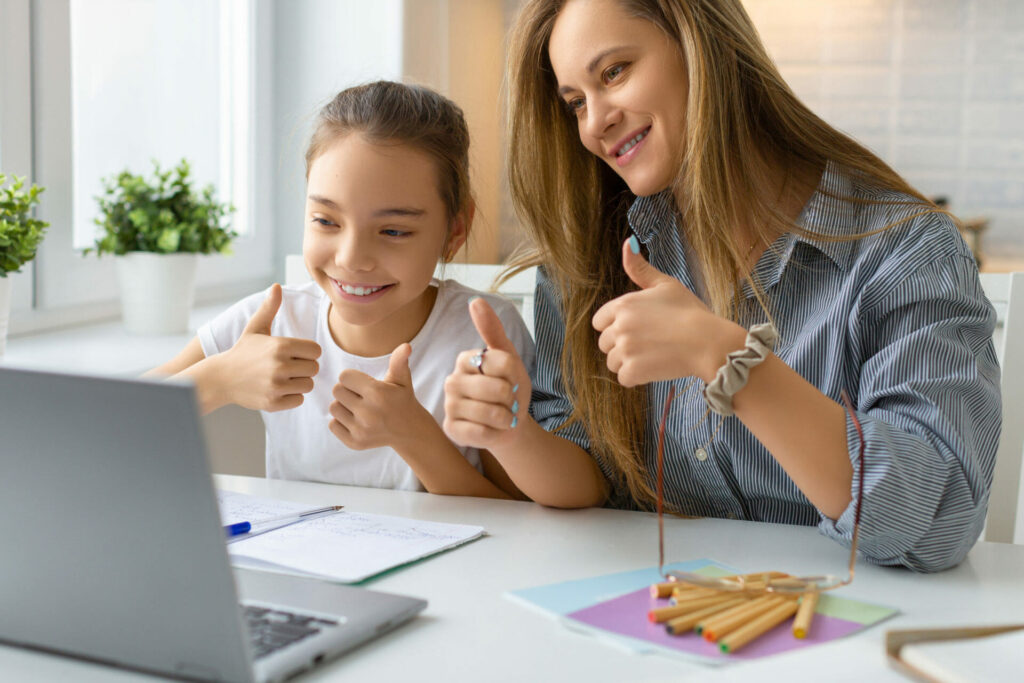 A teenage girl and her mother are holding their thumbs up to a laptop screen