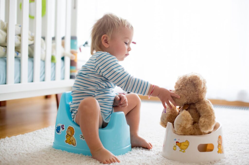 A child being potty trained along with their stuffed toy