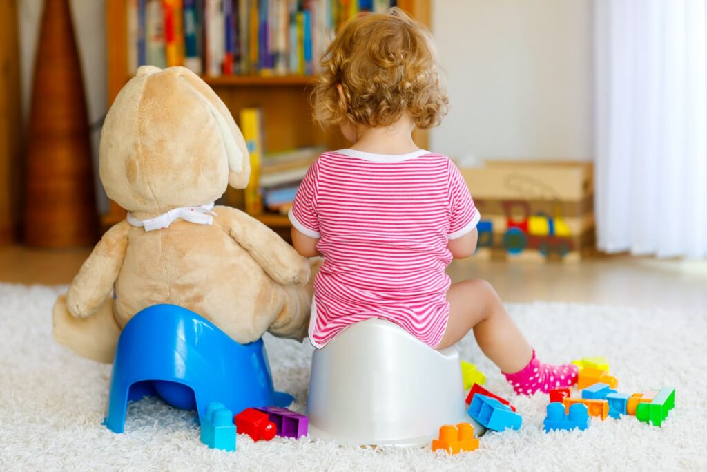 A little girl potty training with her stuffed toy