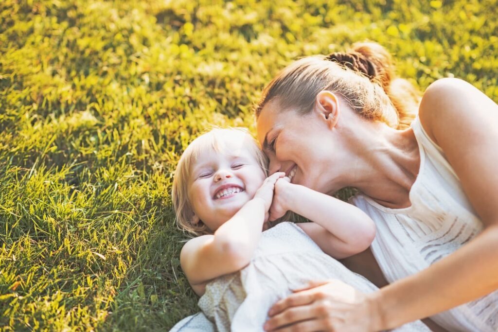 A little girl and her mother lying on the grass and hugging