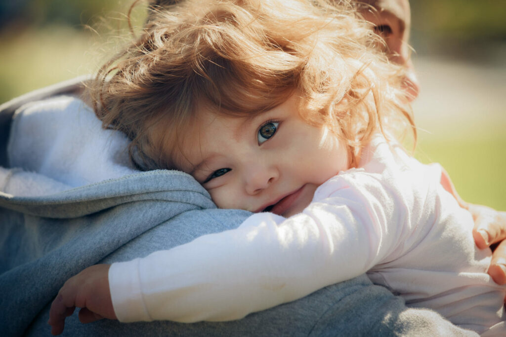 A child hugging their parent whilst looking into the camera